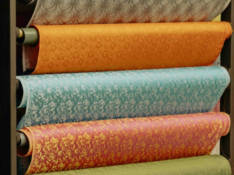 Rolls of patterned upholstery fabric stacked on shelves