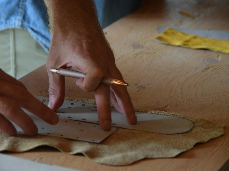 Craftsman tracing a pattern onto a leather hide