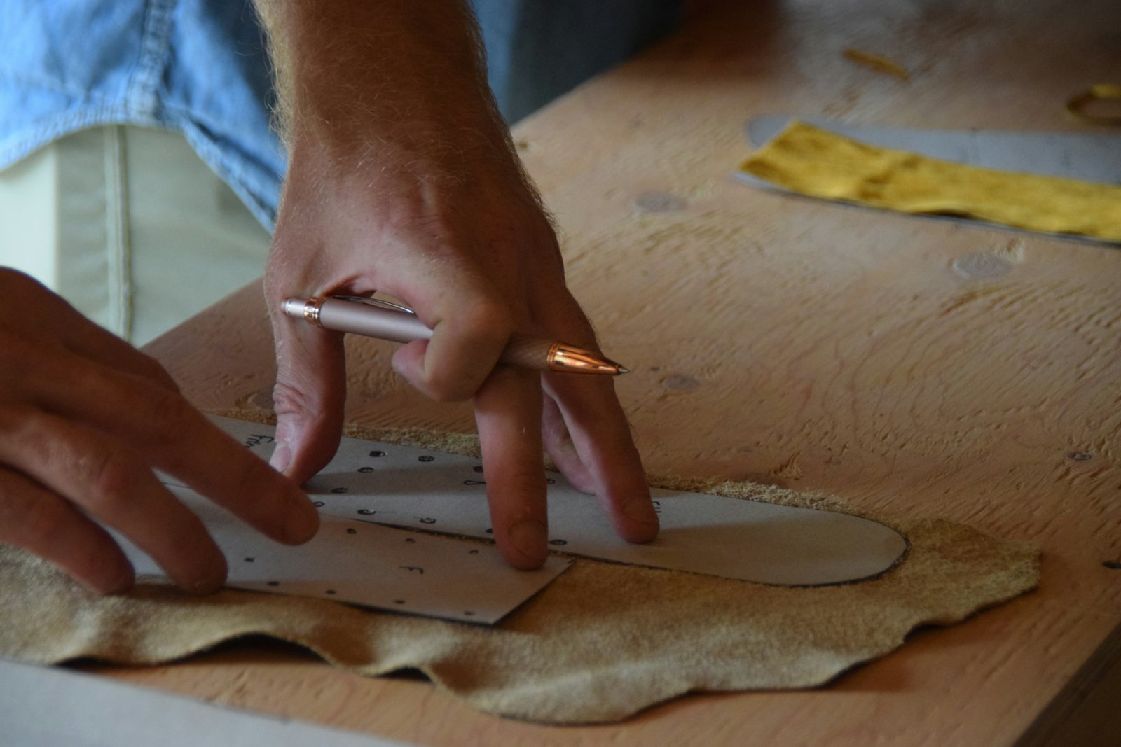 Craftsman tracing a pattern onto a leather hide
